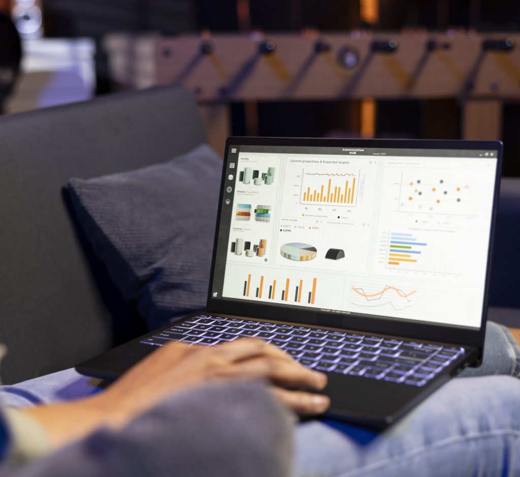 African american guy studying analytics and archived data for a project, reviewing infographics and relaxing on his sofa. Young adult working remotely from the comfort of his home.