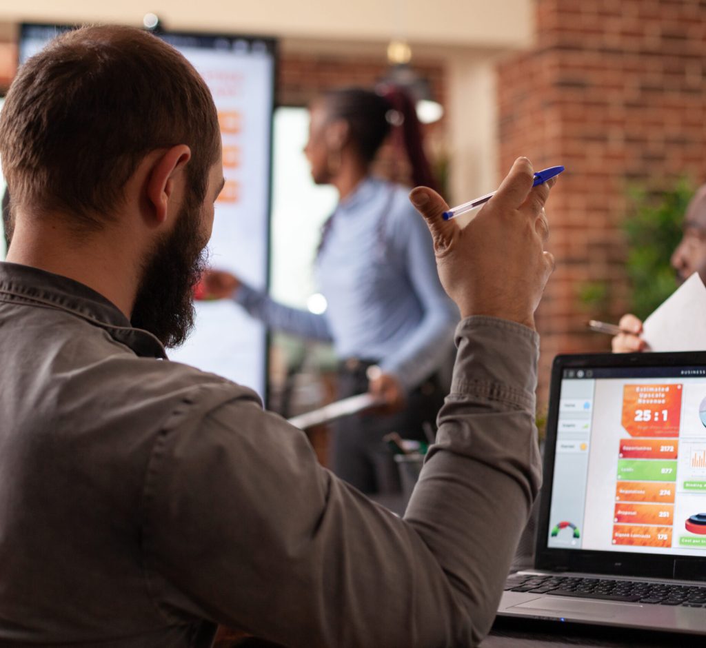 Businessman analyzing company graph on laptop computer working at management presentation during business meeting in startup office. Diverse businesspeople discussing collaboration project